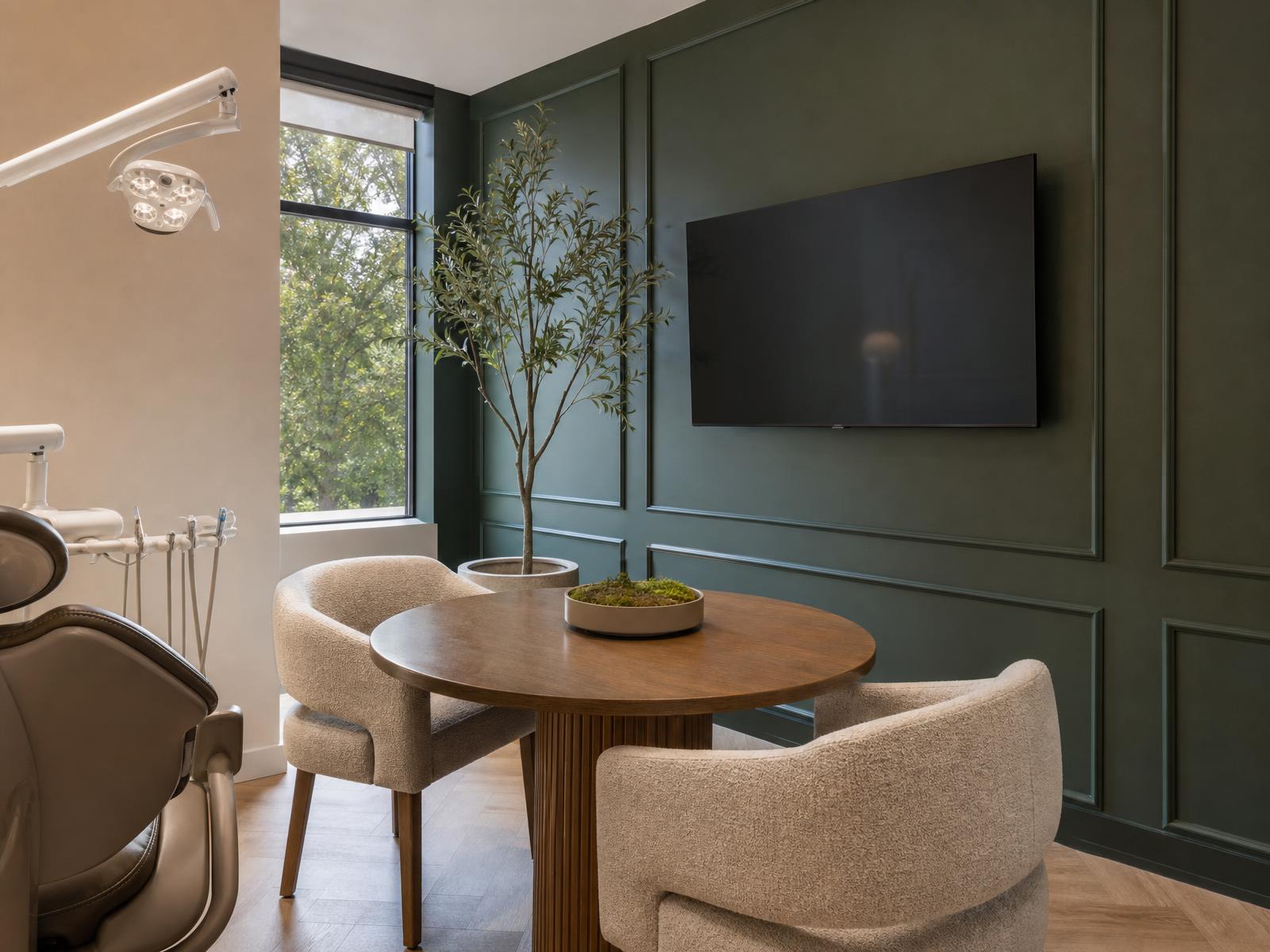 Consultation room with a round table, two chairs, and a forest green wall